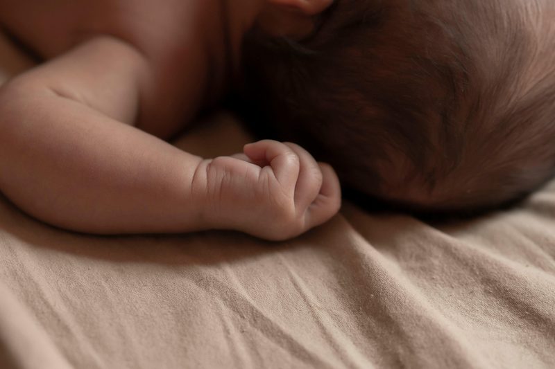 A newborn’s tiny hand resting on a soft blanket