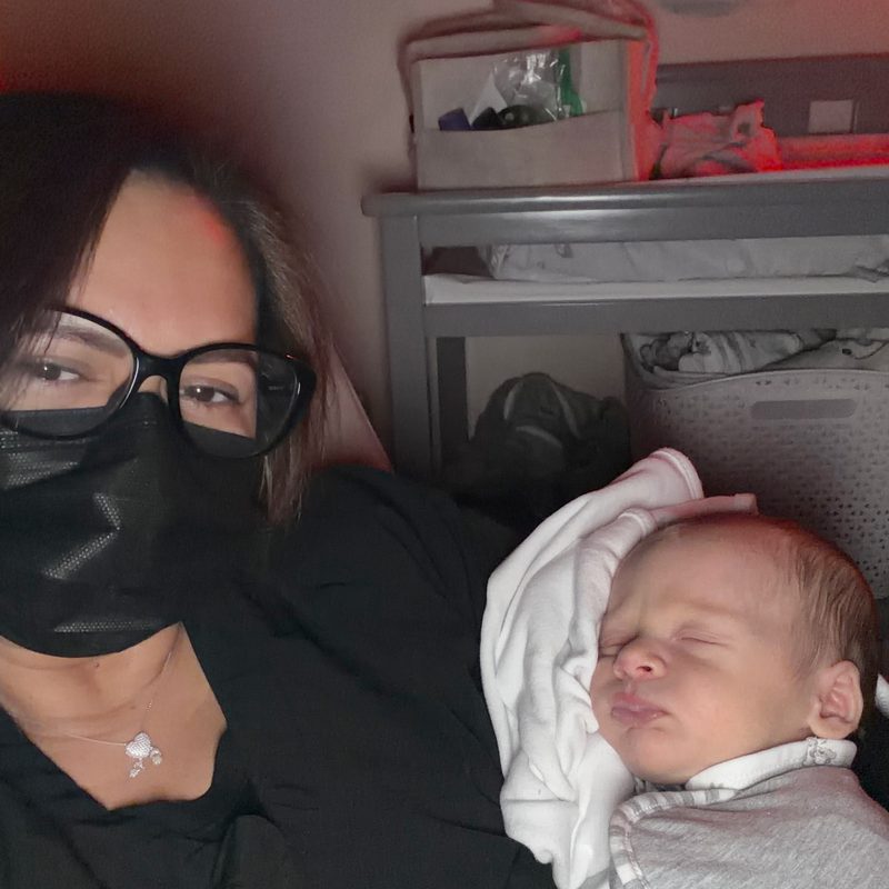 Dorah beside a sleeping newborn under a soft red night light
